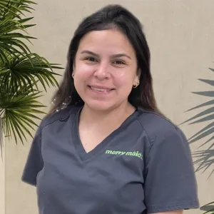smiling woman with a grey merry maids uniform standing in front of a tan wall